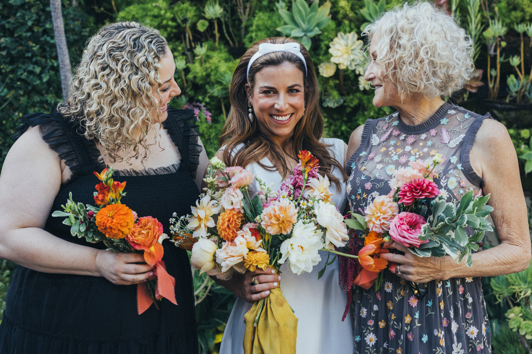 Bride family photo on her wedding day with mother and sister and flowers.