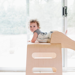 Girl lays on a slide by window