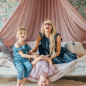 Mother and two daughters being silly on child's bed