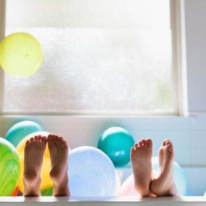 Kid's feet stick out of bathtub with balloons