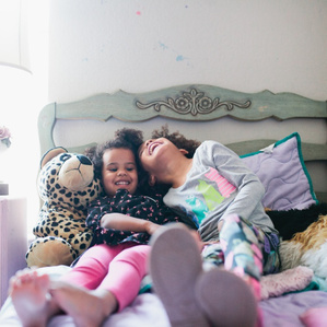 Sisters giggle together on bed
