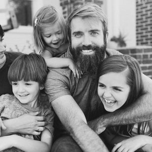 Family sits together laughing in front yard