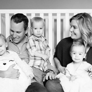 Triplet siblings with parents next to crib
