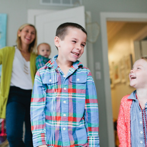 Siblings giggle at each other while Mom smiles at them