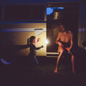 Dad sits with daughter in vintage van holding sparkler fireworks