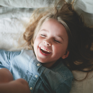 Little girl laughs on bed