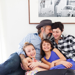 Mom and Dad cuddle with daughters on bed