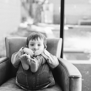 Boy holds legs while sitting on chair