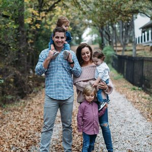 Family stands on driveway in Fall with leaves