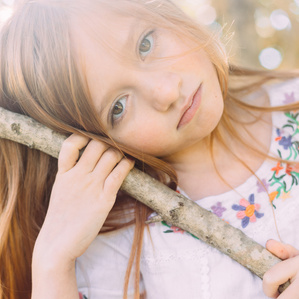Red head girl hangs on tree branch