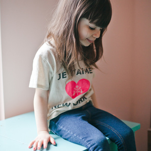 Little girl sits on dresser smiling