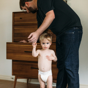 Dad holds sons hand while looking for clothing