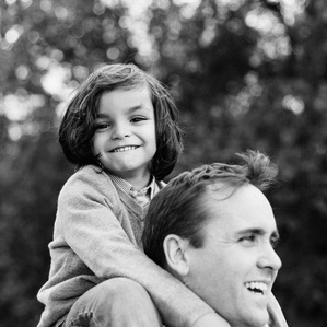 Father holds son on shoulders outside