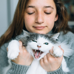 Teen girl holds cat with mouth open meow