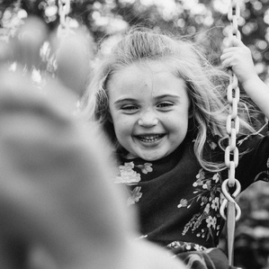 Girl on swing set sticks foot out by camera