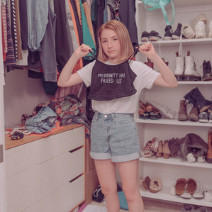 Teen girl holds homemade t shirt in messy closet