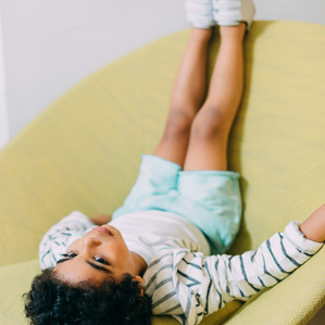 Boy sits upside down in big yellow chair
