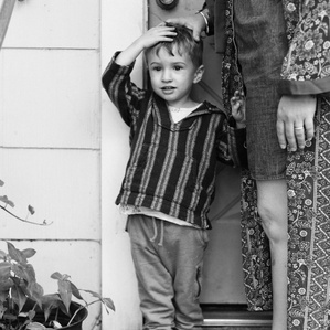 Boy stands next to mom's legs by backdoor