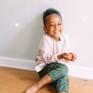 Smiling little girl sitting on floor with disco lights