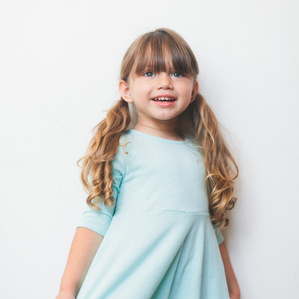 Little girl with pigtails smiles in blue dress