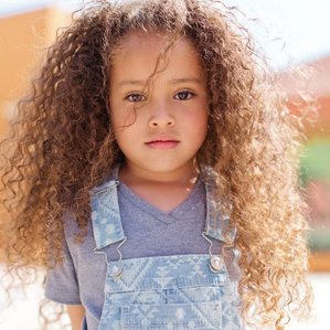 Little girl with big, curly hair stares at camera 