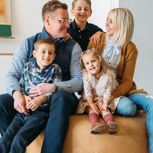 Family sits together smiling in living room