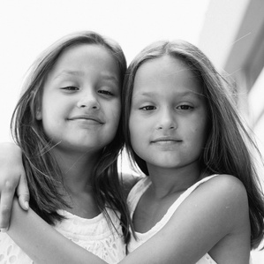 Twin girls stand next to each other hugging