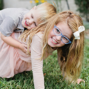 Girl in glasses holds little brother on her back