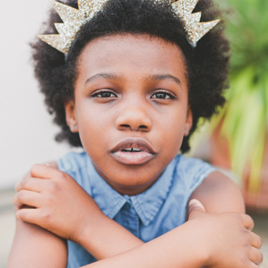 Girl wearing crown headband looks into camera