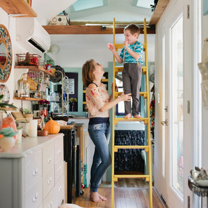 Mother and son stand in tiny house with dog