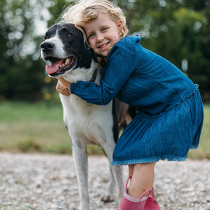 Girl hugs beloved pet dog while wearing rainboots