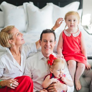 Family at Christmas time sits together in bedroom while mom fixes daughters hair
