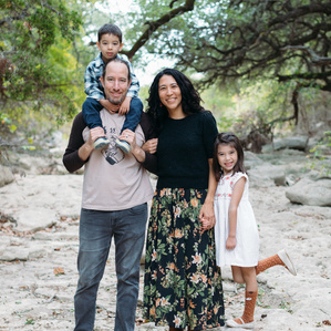 Son sits on Dad's shoulders while Mom and daughter stands in dried creek bed in Austin Texas park