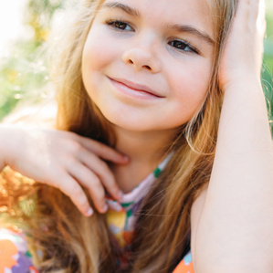 Little girl near flowers smiles and looks away from the camera