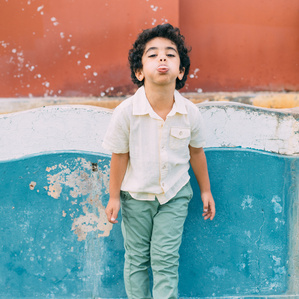 Boy blowing raspberries with tongue out being silly next to colorful fountain