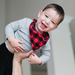 Smiling boy gets lifted into air by Dad