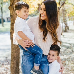 Mother stands with sons under tree in Fall 