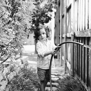 Boy holds water hose in backyard