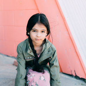 Girl leans on ground next to colorful wall