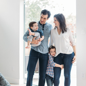 Family of 4 stands together inside bedroom