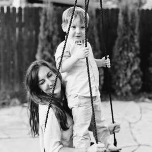 Mom sits on swing with son in backyard