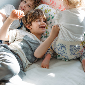 3 siblings play together on bed