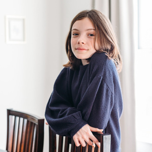 Teen girl stands in dining room looking at camera