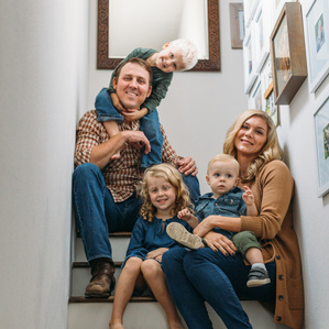 Family of 5 sits on stairs inside home