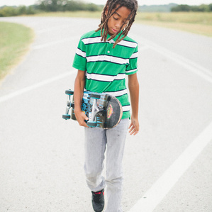 Boy walks with skateboard in the street