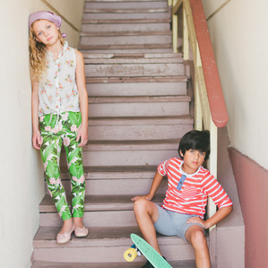 Two fashionable kids sit on steps with skateboard