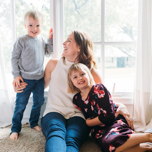 Mother laughs along with son and daughter next to window