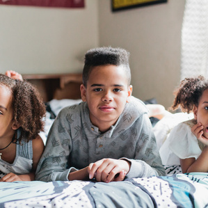 3 siblings laying on bed together