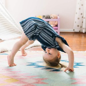 Little girl stands upside down in playroom