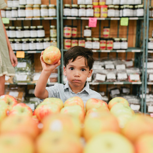 Boy holds apple in farmers market store